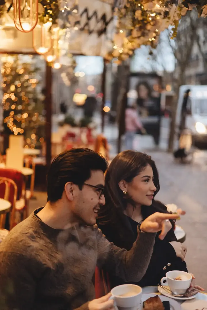 Couple laughing Paris cafe terrace Christmas lights winter