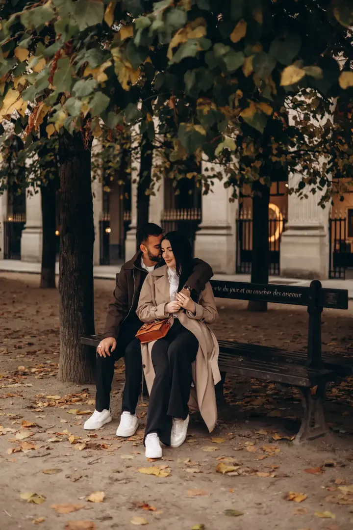 Couple sitting bench autumn leaves Palais Royal Paris