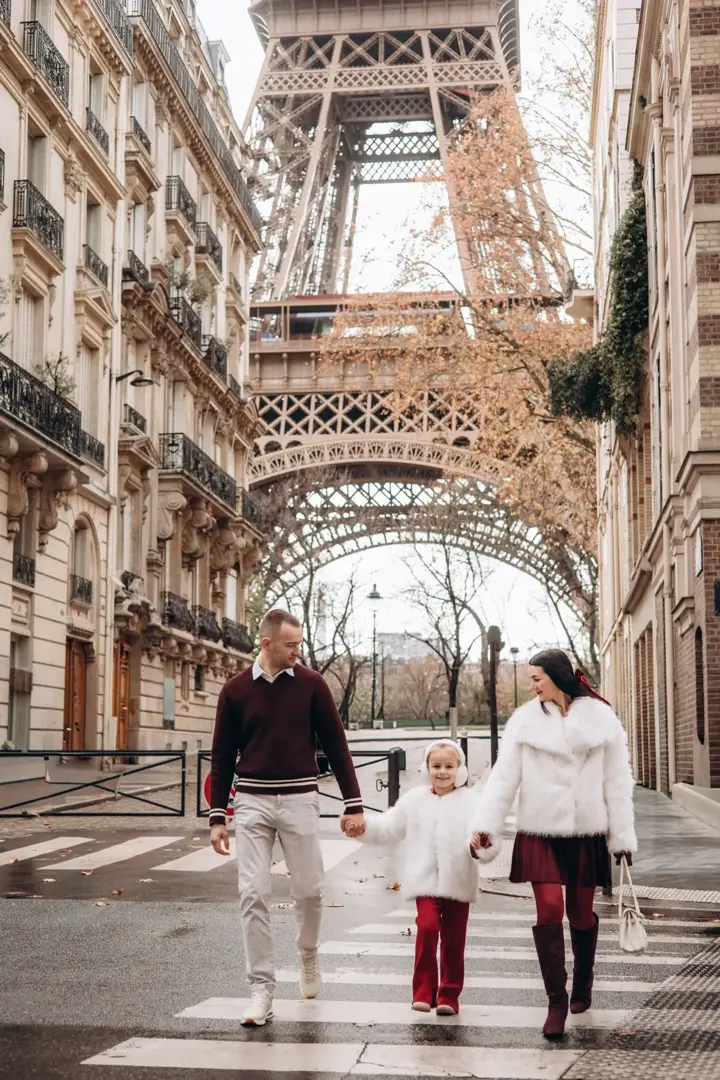 Family walking under Eiffel Tower arch Paris