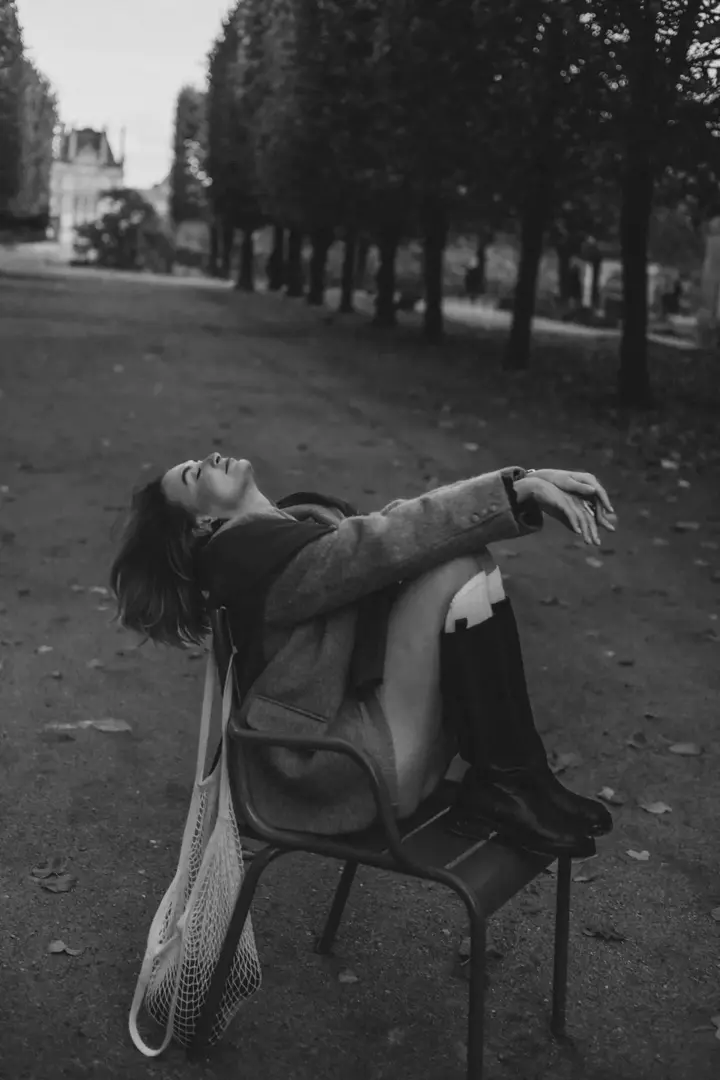 Woman leaning back chair park alley black white Paris